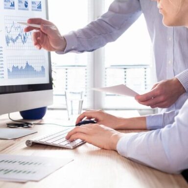 Two people looking at a computer monitor.