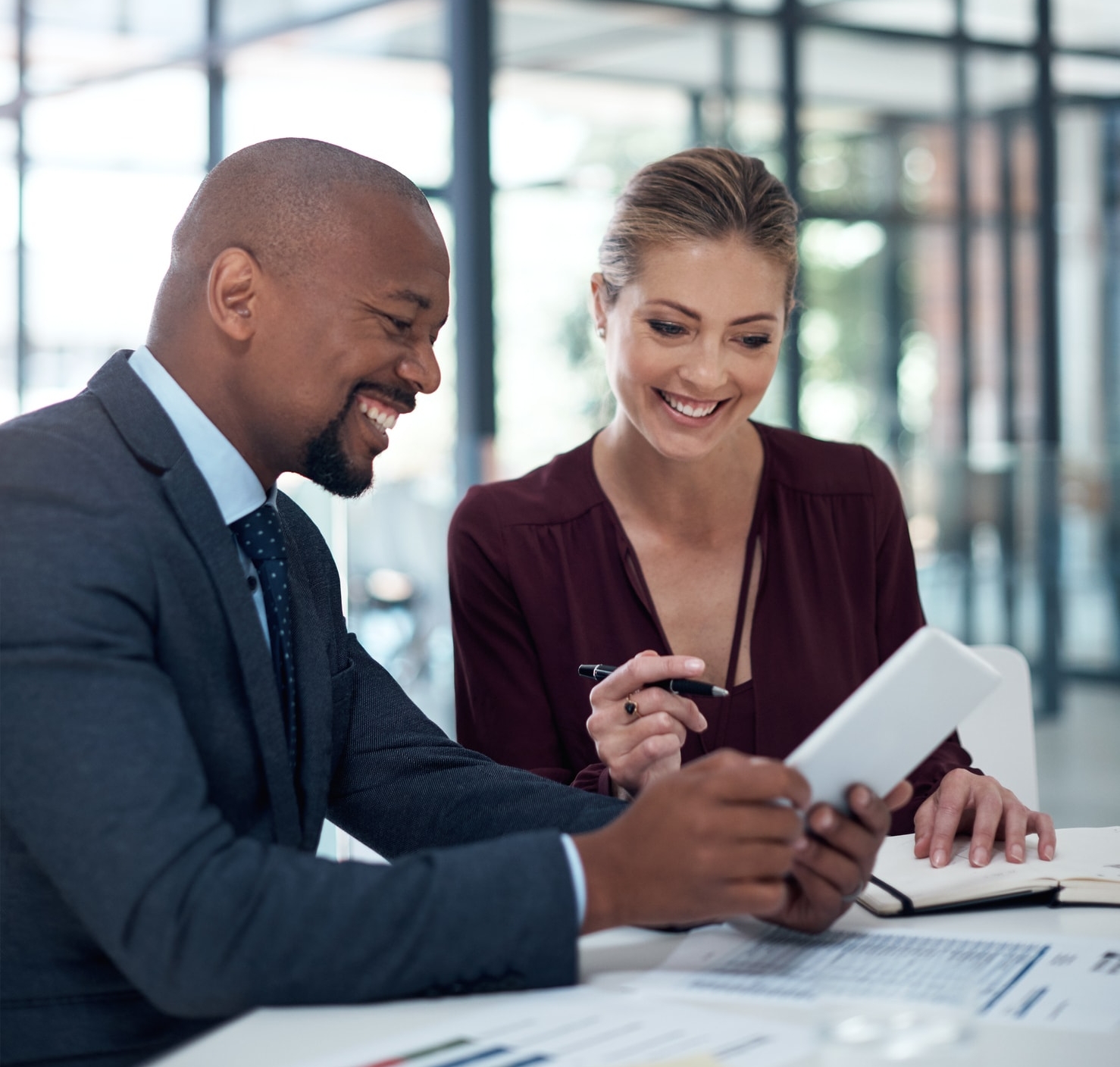 Two smiling business people looking at notepad.