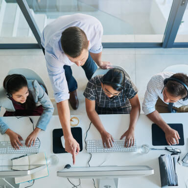 View from on high of workers in front of a computer monitor.