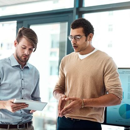 Two men look at a tablet screen