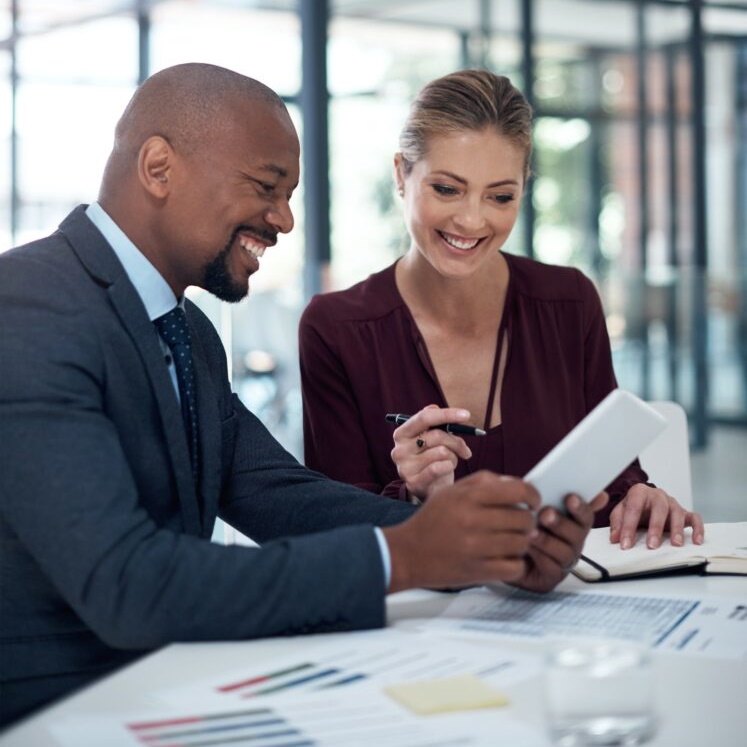 Two smiling business people looking at notepad.