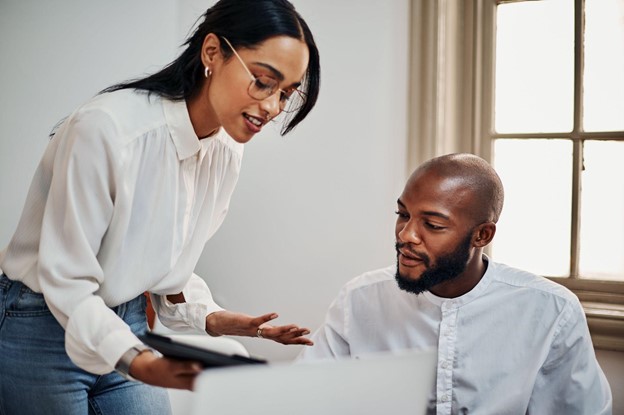 Une homme et une femme parlent tout en regardant l'écran d'une tablette.