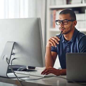 A man thoughtfully looking at his computer monitor.