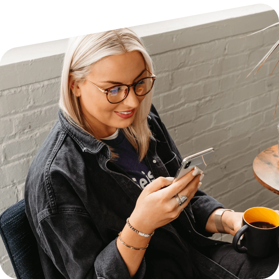 Woman looking at her phone and drinking a beverage.