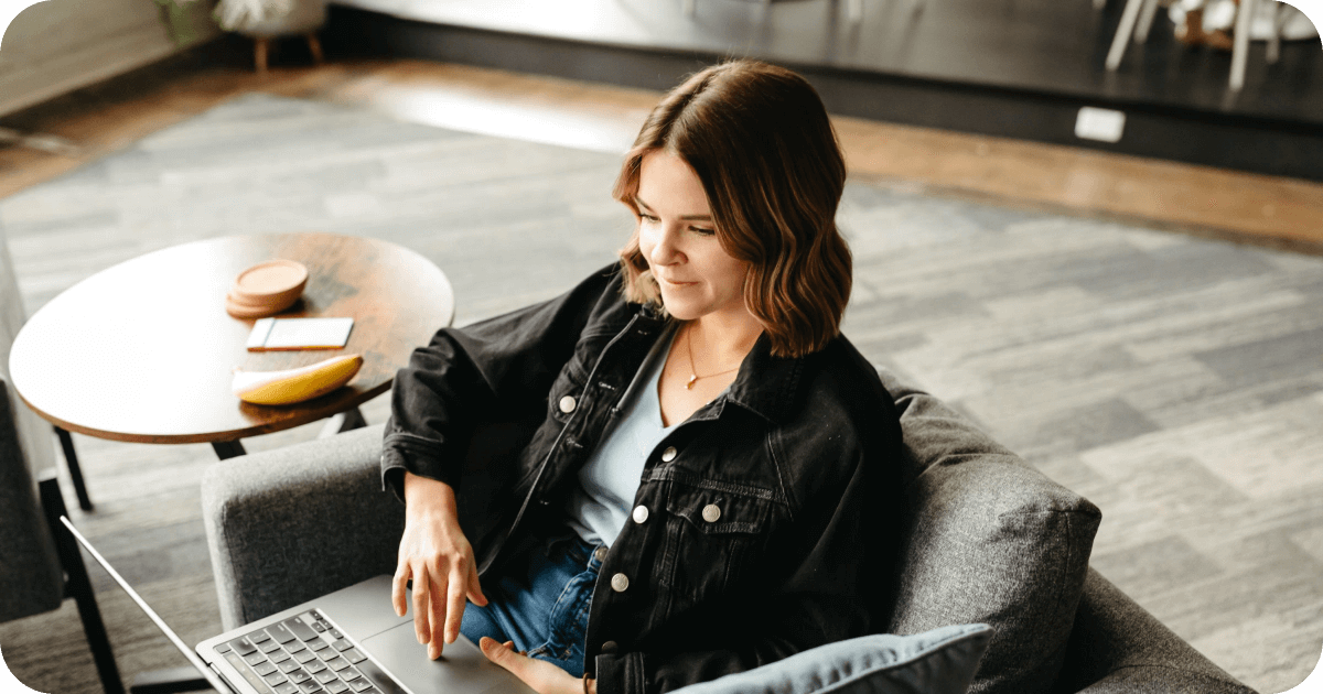 A seated woman browses on her laptop.