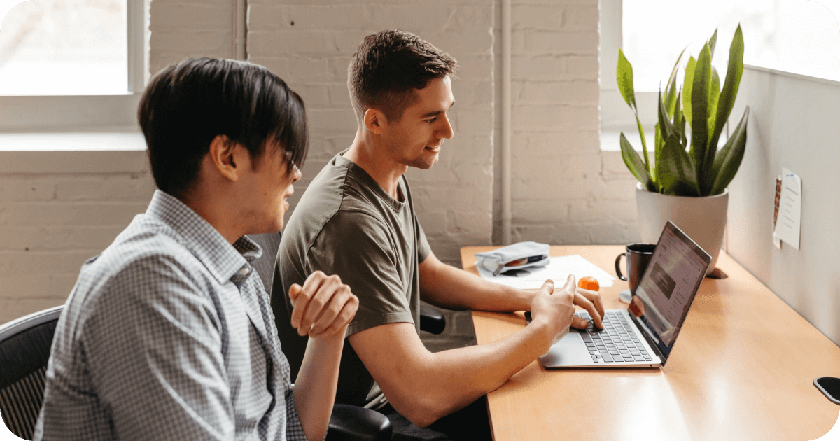 Two people looking at a laptop and talking.