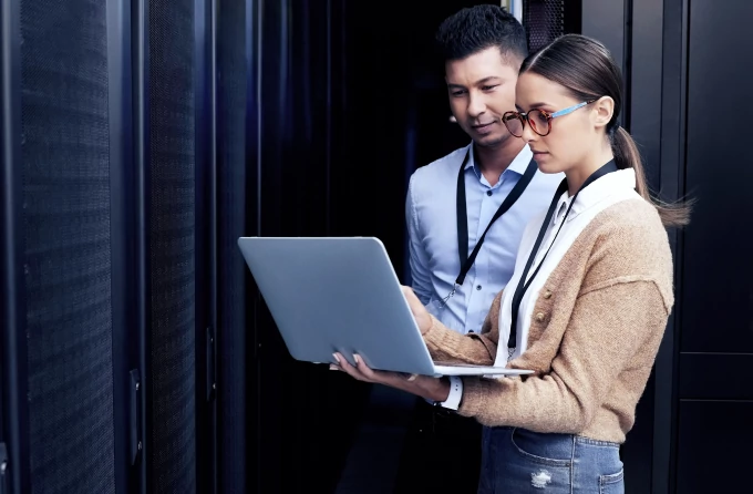 Two security experts look at the screen of a laptop.