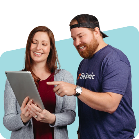 Two smiling coworkers viewing a tablet.