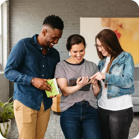 Three smiling coworkers looking at a Notebook screen.