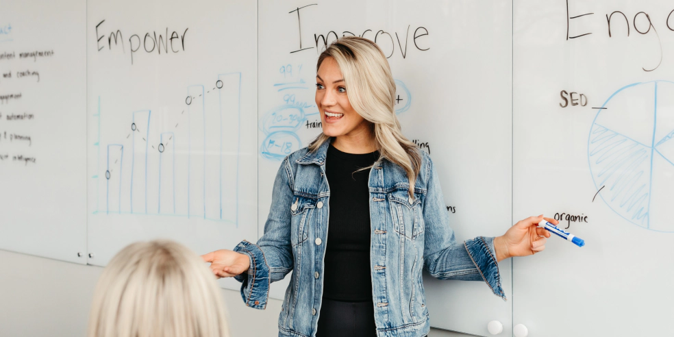 A woman point to something on a whiteboard.